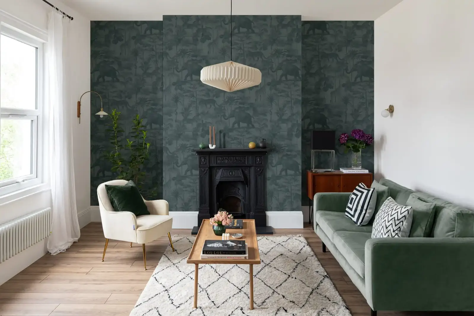 Dark green patterned wallpaper on a chimney breast around a black cast-iron fireplace